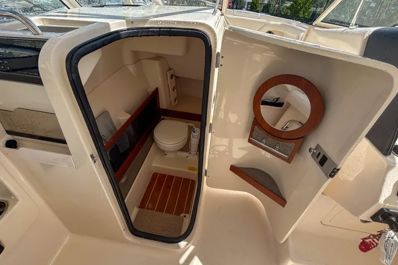 Slide: The Image of 2019 Grady-White Freedom 275 boat interior with compact bathroom and wooden accents. - 9
