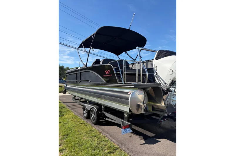 Slide: The Image of 2026 Whisper C25 Splash Pad pontoon boat on trailer, featuring sleek design and canopy. - 17