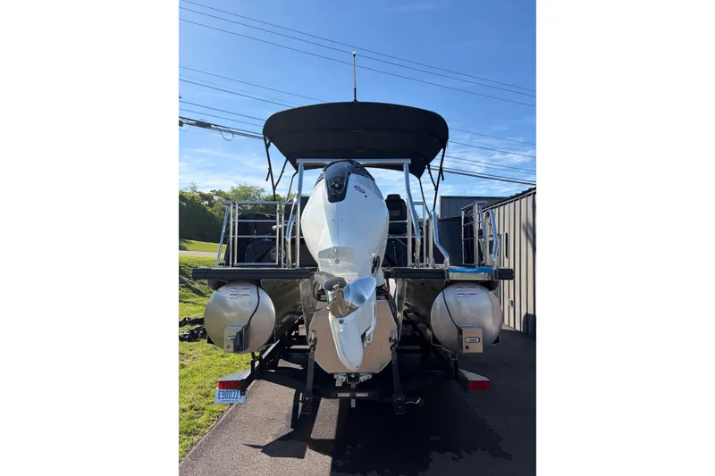 Slide: The Image of 2026 Whisper C25 Splash Pad boat with dual pontoons and canopy, parked outdoors. - 18