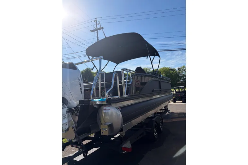 Slide: The Image of 2026 Whisper C25 Splash Pad pontoon boat with canopy and Honda engine, parked outdoors. - 19