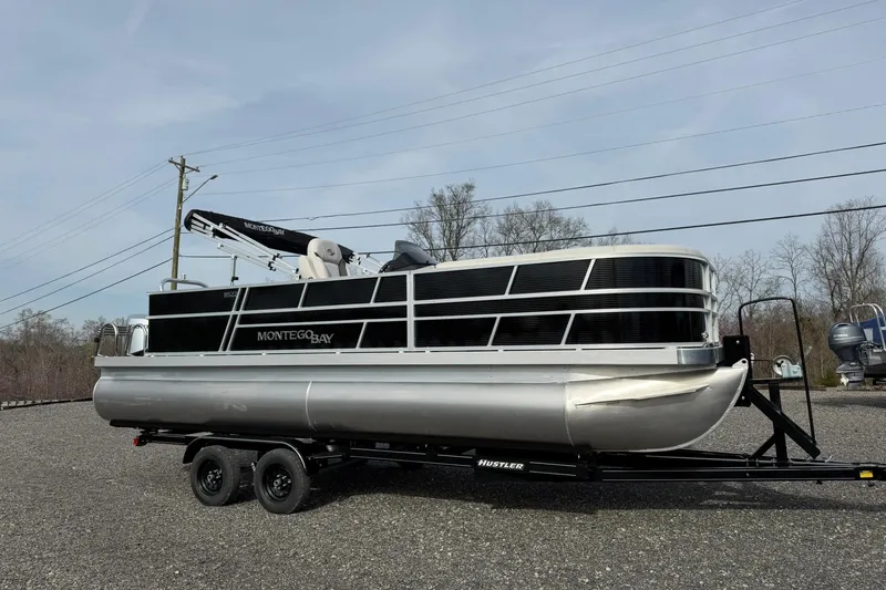 Slide: The Image of 2026 Montego Bay 140HP pontoon boat on trailer, parked outdoors. - 7