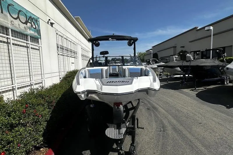 Slide: The Image of 2025 Malibu Wakesetter 23 MXZ boat on trailer, parked outdoors under clear blue sky. - 4