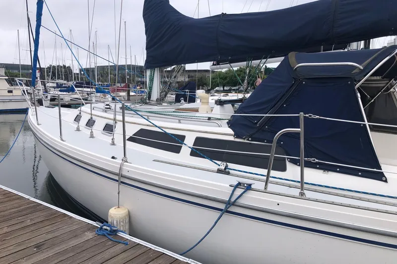 Slide: The Image of 1992 Catalina 34 sailboat docked at marina, featuring blue canvas covers and sleek white hull. - 10