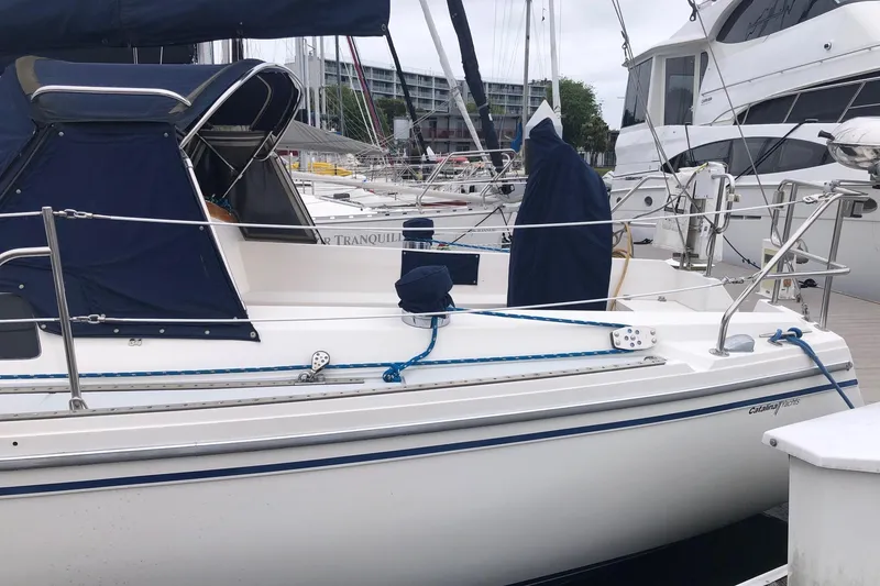 Slide: The Image of 1992 Catalina 34 sailboat docked at marina, featuring blue covers and sleek design. - 11