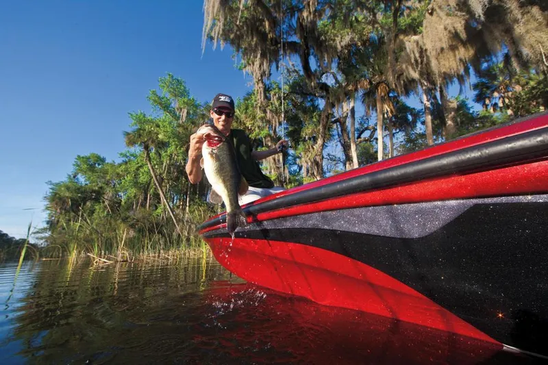 Slide: The Image of Manufacturer Provided Image: Man fishing from a 2013 Nitro Z-8 boat, holding a large fish in a scenic lake. - 43