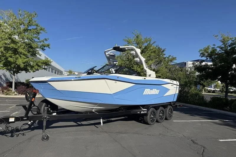 Slide: The Image of 2025 Malibu Wakesetter 26 LSV boat on trailer, parked outdoors under clear blue sky. - 1