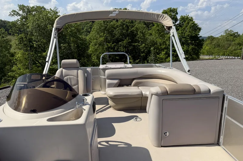 Slide: The Image of 2015 Starcraft Stardeck 216 Cruise-N-Fish boat with beige seating and canopy, surrounded by greenery. - 12