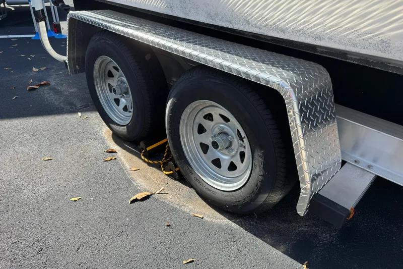 Slide: The Image of Trailer wheels of a 2018 Hurricane SunDeck 2400 OB, parked on asphalt with metal fenders. - 27
