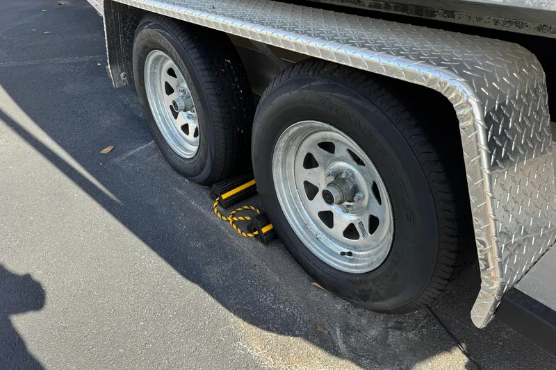 Slide: The Image of Trailer wheels with chocks on a 2018 Hurricane SunDeck 2400 OB boat trailer. - 28