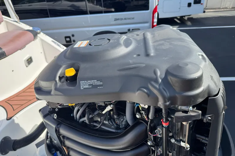 Slide: The Image of 2018 Hurricane SunDeck 2400 OB boat engine close-up in a parking lot. - 8