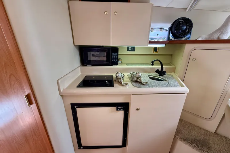 Slide: The Image of 2002 Cruisers Yachts 2870 Express galley with sink, stove, microwave, and storage cabinets. - 17