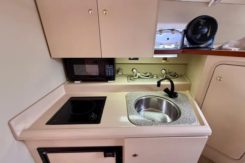 Slide: The Image of 2002 Cruisers Yachts 2870 Express galley with sink, stovetop, and microwave. - 18