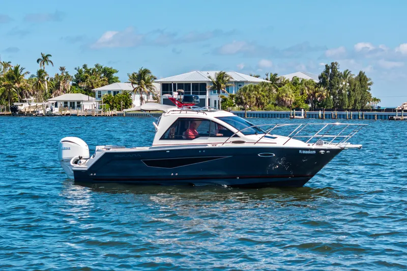 The Image of 2026 Solara S-250 Coupe boat cruising on a sunny day near waterfront homes. - 1