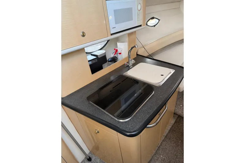 Slide: The Image of Compact kitchen area in a 2001 Maxum 2800 SCR boat, featuring a sink and stove. - 8