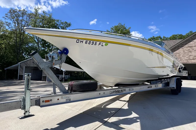 Slide: The Image of 2000 Fountain 27 Fever boat on trailer, parked outdoors under clear blue sky. - 10