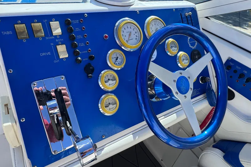 Slide: The Image of Control panel of a 2000 Fountain 27 Fever boat with blue steering wheel and gauges. - 19
