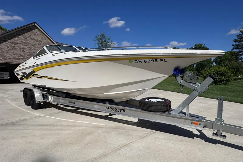 Slide: The Image of 2000 Fountain 27 Fever speedboat on trailer, parked in driveway under clear blue sky. - 4