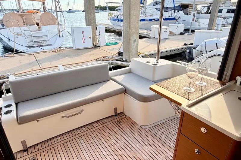 Slide: The Image of Beneteau Swift Trawler 41 Fly 2021, elegant deck seating with wine glasses, docked at marina. - 11