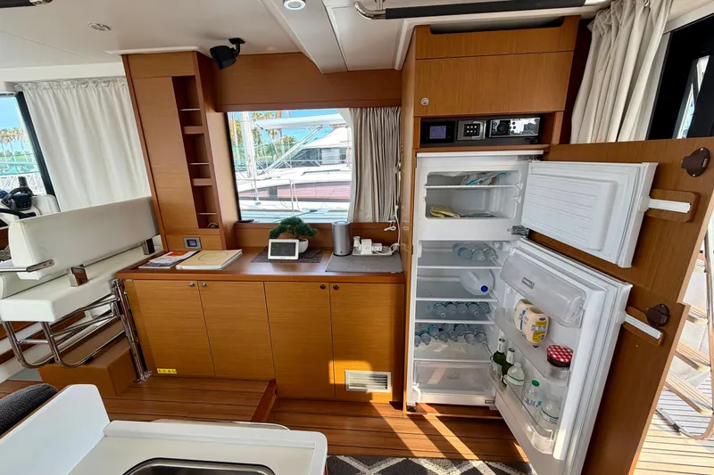 Slide: The Image of Interior of 2021 Beneteau Swift Trawler 41 Fly with open fridge and wooden cabinetry. - 30