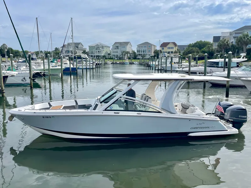 Slide: The Image of 2021 Chaparral 300 OSX boat docked in marina, surrounded by yachts. - 4