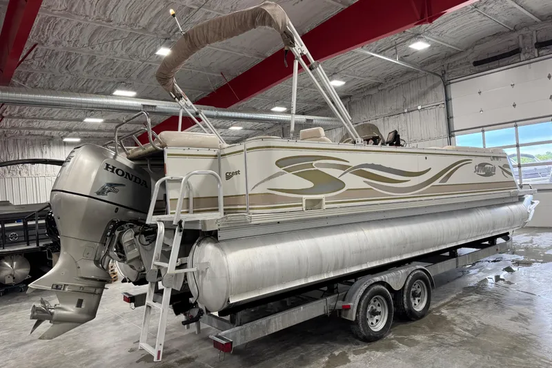 Slide: The Image of 2005 Crest 25 Savanna pontoon boat with Honda outboard motor in a spacious indoor storage facility. - 4