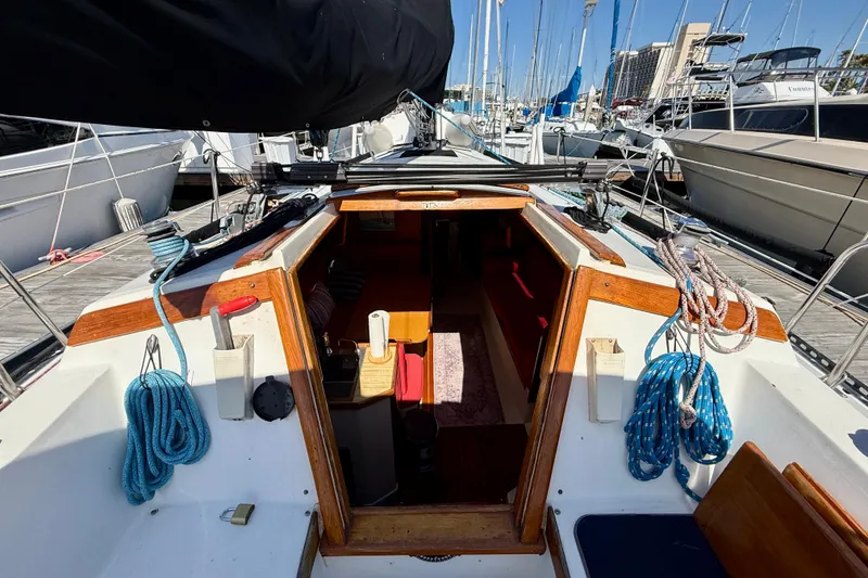 Slide: The Image of 1985 Catalina 38 sailboat interior view at marina, showcasing cockpit and cabin entrance. - 14