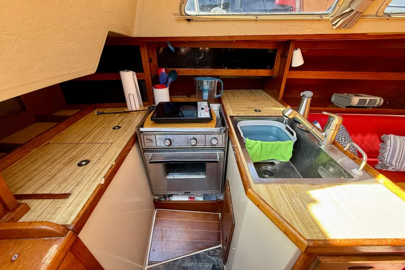 Slide: The Image of Compact kitchen in a 1985 Catalina 38 sailboat with stove, sink, and wooden cabinetry. - 16