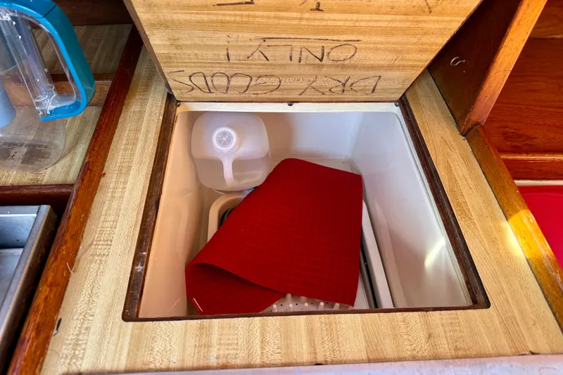 Slide: The Image of Built-in cooler on 1985 Catalina 38 sailboat with red mat and water jug. - 19