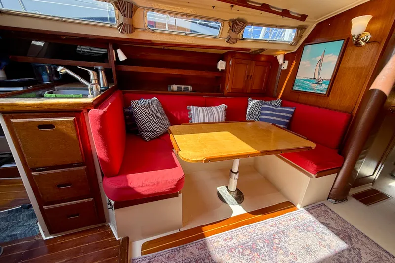 Slide: The Image of Cozy interior of 1985 Catalina 38 sailboat with red seating and wooden table. - 26