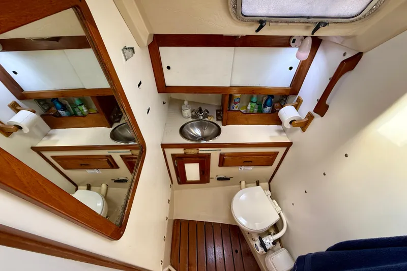 Slide: The Image of 1985 Catalina 38 yacht bathroom with wooden accents, mirror, sink, and toilet. - 32