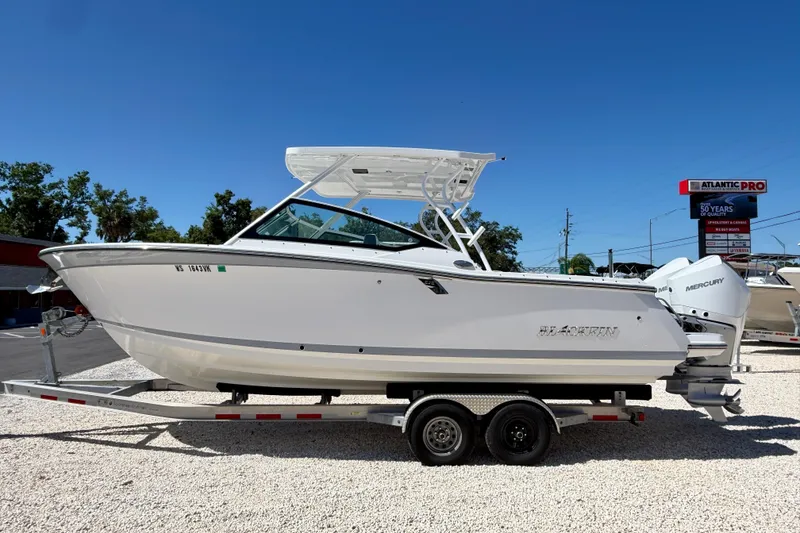 The Image of 2023 Blackfin 272 DC boat on trailer, displayed outdoors under clear blue sky. - 0
