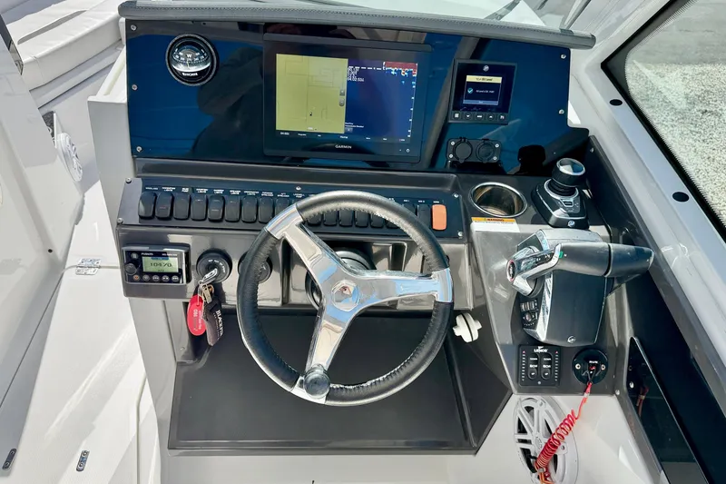Slide: The Image of 2023 Blackfin 272 DC helm with steering wheel, navigation display, and control panel. - 13