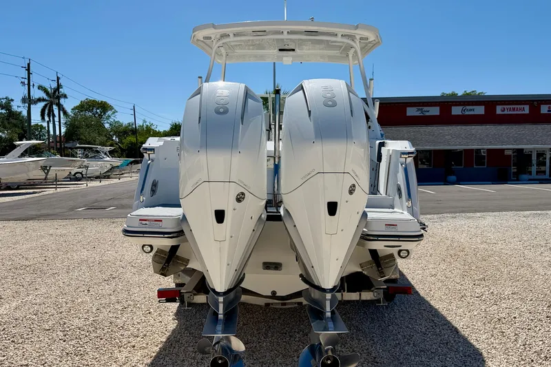 Slide: The Image of 2023 Blackfin 272 DC boat with dual outboard engines, parked on gravel lot. - 6
