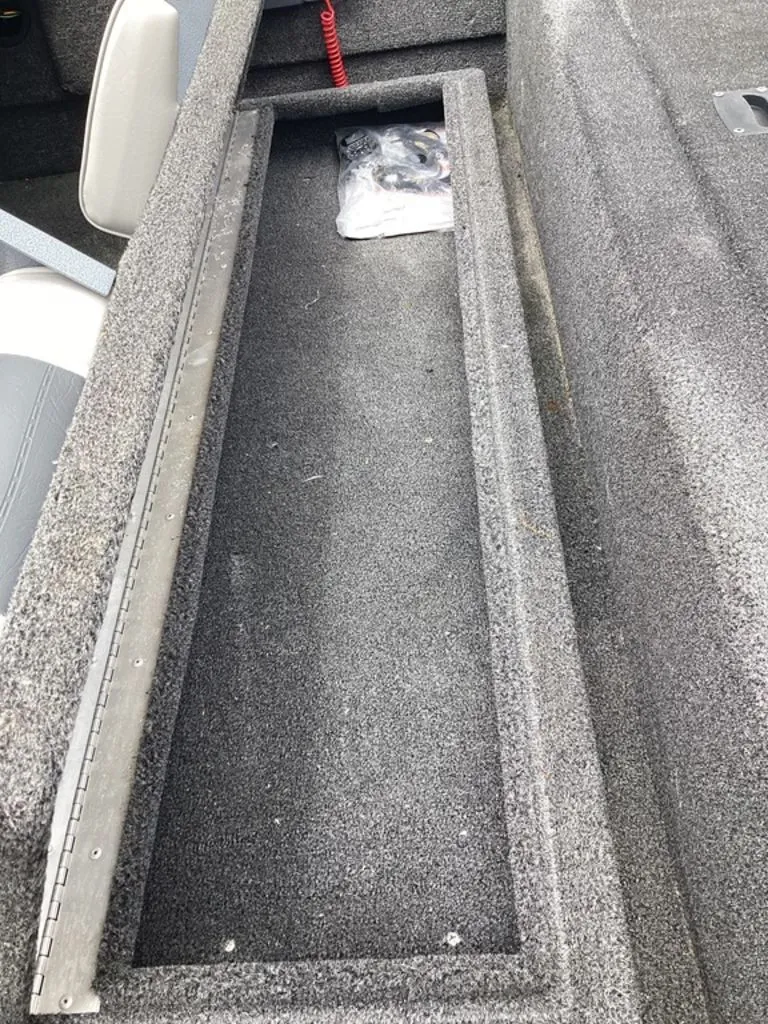 Slide: The Image of Lowe Stinger 18 HP 2013 boat storage compartment with gray carpet. - 34