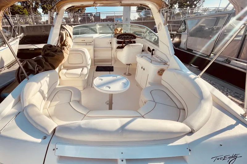 Slide: The Image of 2001 Sea Ray 280 boat interior with white seating and helm, docked in sunlight. - 14