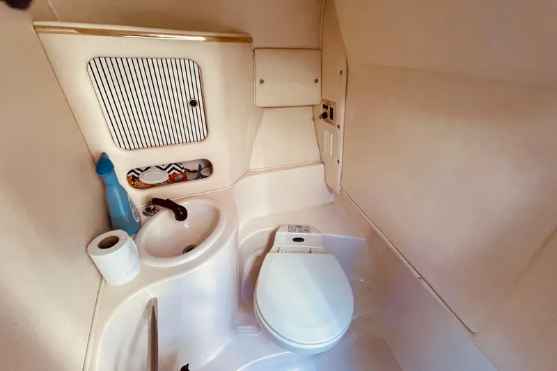 Slide: The Image of Compact bathroom in a 2001 Sea Ray 280 boat, featuring a toilet and sink. - 25
