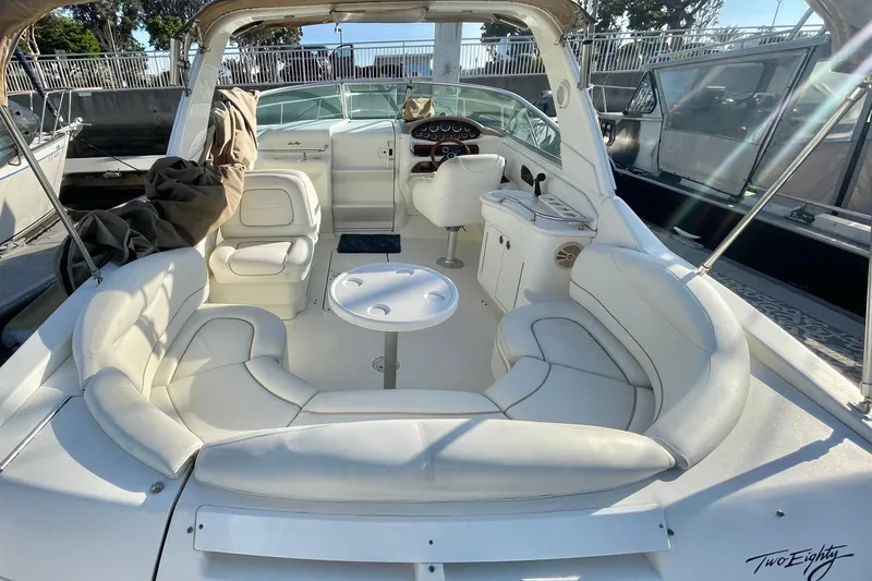Slide: The Image of 2001 Sea Ray 280 boat interior with white seating and helm, docked in sunlight. - 6
