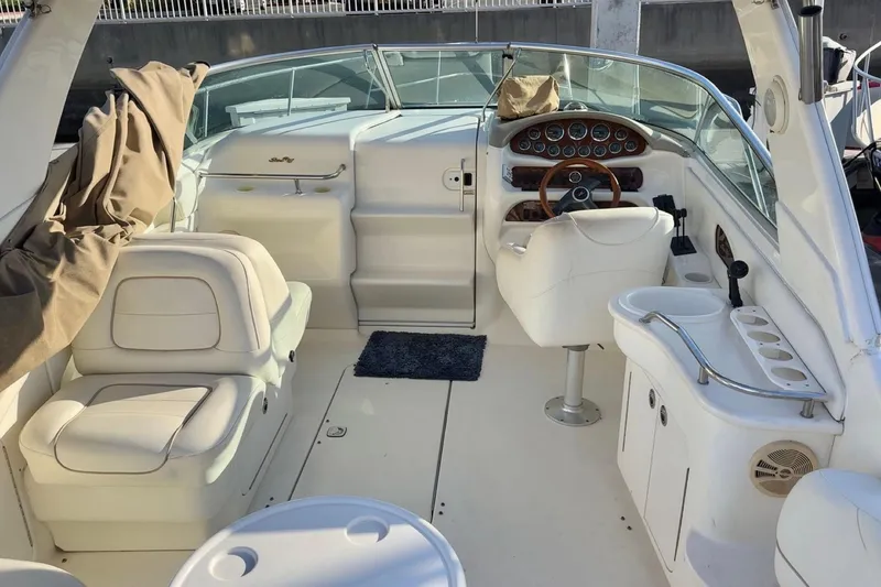 Slide: The Image of 2001 Sea Ray 280 boat interior with white seating and wooden dashboard. - 7