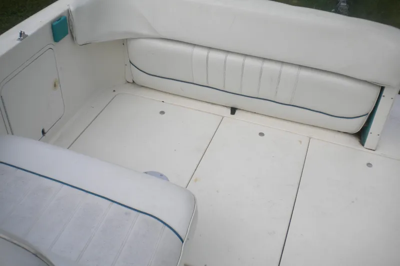 Slide: The Image of Interior seating of a 1996 Sea Ray 270 Sundancer boat, featuring white cushioned benches. - 12
