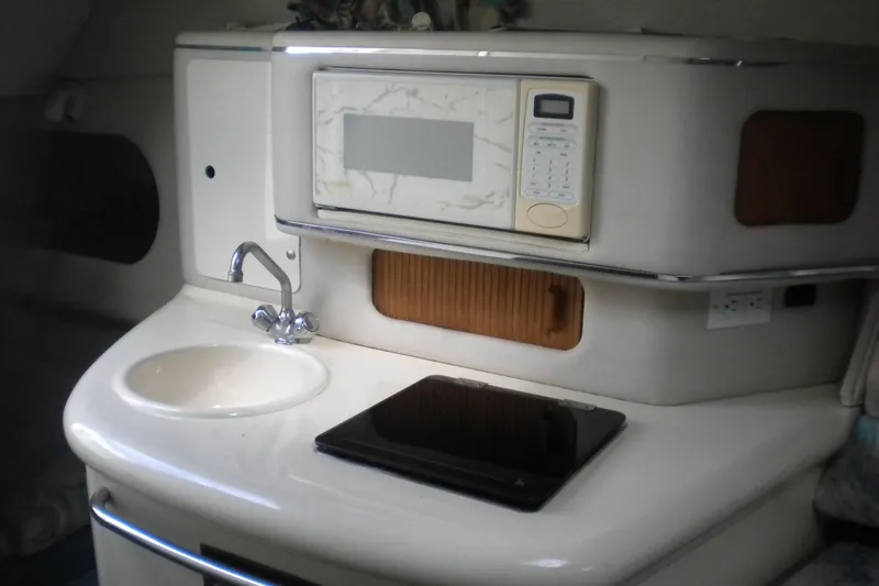 Slide: The Image of 1996 Sea Ray 270 Sundancer galley with sink, microwave, and stovetop. - 16