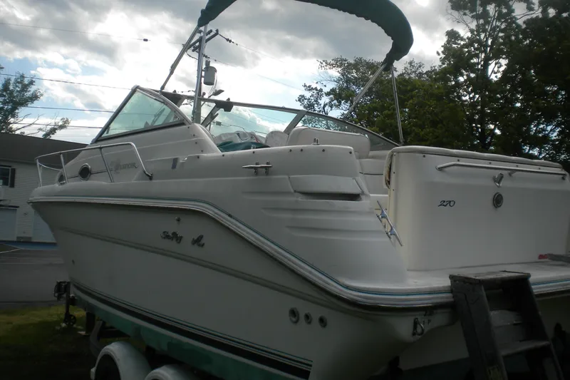 Slide: The Image of 1996 Sea Ray 270 Sundancer boat on trailer, parked outdoors under cloudy sky. - 4