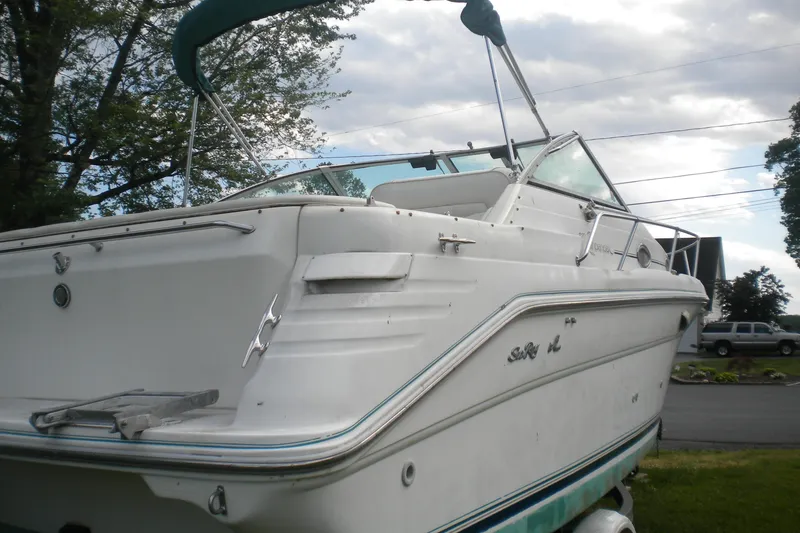 Slide: The Image of 1996 Sea Ray 270 Sundancer boat with white exterior, docked outdoors under a cloudy sky. - 5