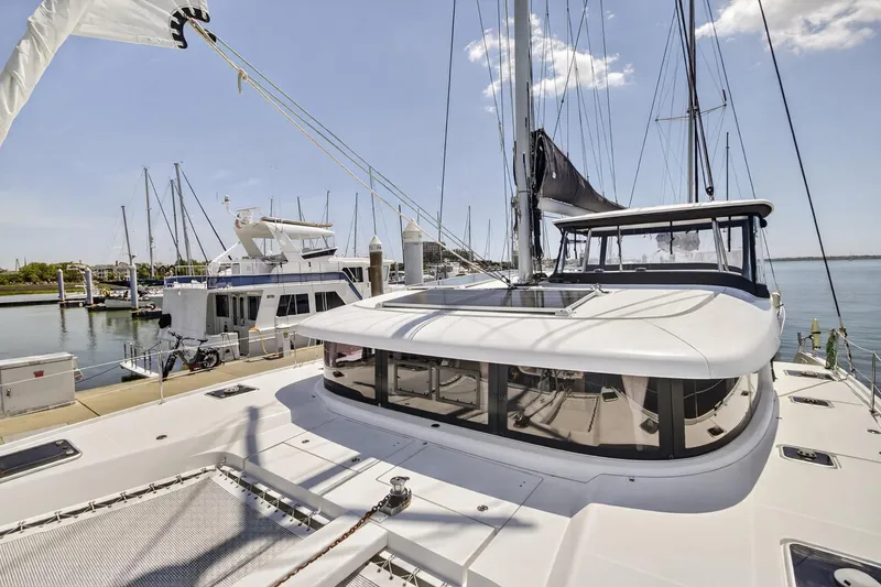 Slide: The Image of 2018 Lagoon 42 catamaran docked at marina, showcasing sleek design and spacious deck. - 11