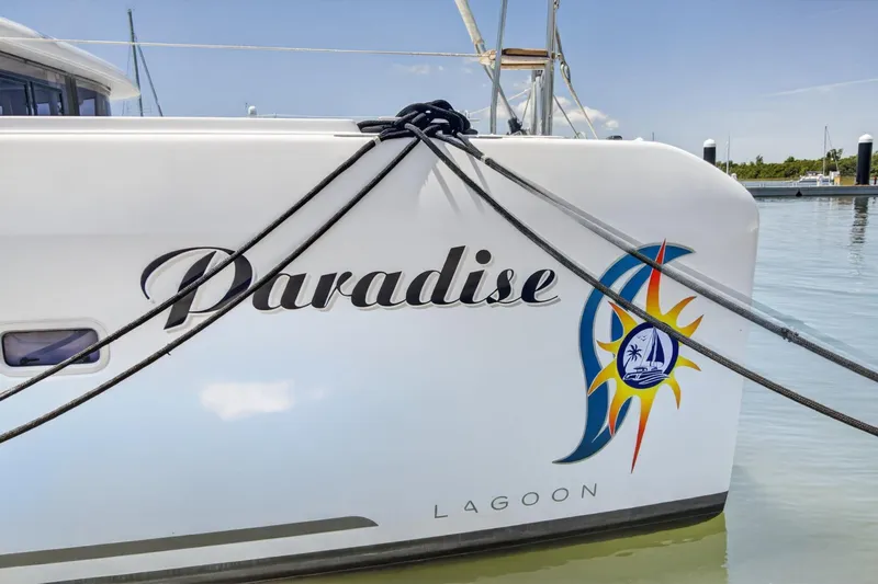 Slide: The Image of Lagoon 42 catamaran named "Paradise" docked, featuring colorful nautical graphics. - 3