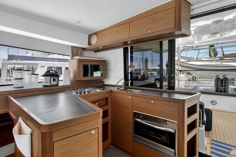 Slide: The Image of Modern kitchen interior on 2018 Lagoon 42 yacht with wood cabinetry and marina view. - 32
