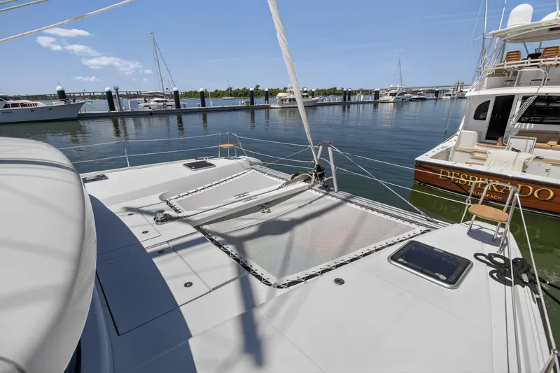 Slide: The Image of 2018 Lagoon 42 catamaran docked at marina, featuring spacious deck and netting. - 8