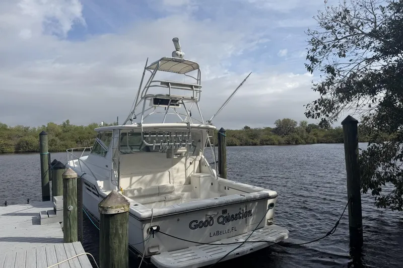 Slide: The Image of 2000 Tiara Yachts 4100 Open docked by a serene riverbank under cloudy skies. - 10