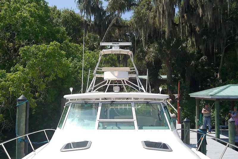 Slide: The Image of 2000 Tiara Yachts 4100 Open docked amidst lush greenery. - 16