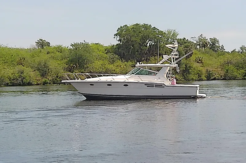 Slide: The Image of 2000 Tiara Yachts 4100 Open cruising on a calm river with lush greenery. - 5