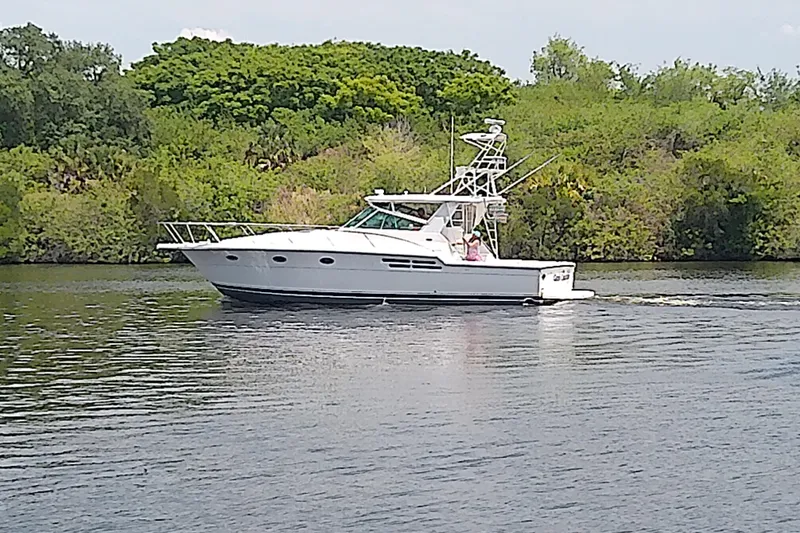 Slide: The Image of 2000 Tiara Yachts 4100 Open cruising on a serene river with lush greenery. - 6